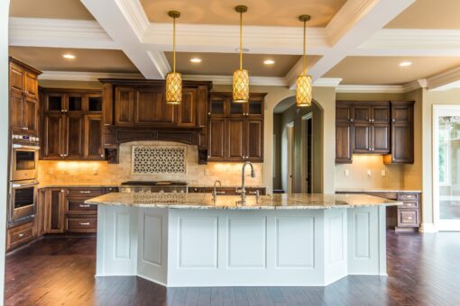 Kingfogl custom home kitchen with dark cabinetry, white island and coffered ceiling