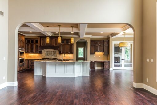 Kingfogl custom home kitchen viewed through an arched opening with coffered ceiling