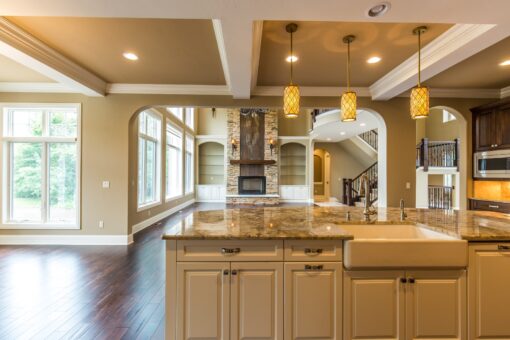 Kingfogl custom home kitchen with cream cabinetry, granite island and amber pendants
