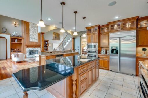 Kingfogl custom home kitchen with black granite island and warm wood cabinetry