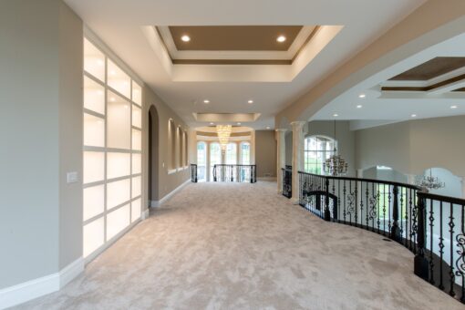 Kingfogl custom home loft hallway with iron railing and lit wall panels