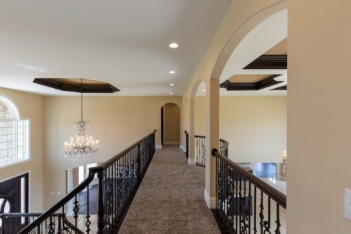 Kingfogl custom home loft walkway with iron railing and view to the chandelier