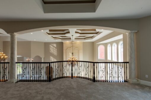 Kingfogl custom home loft with iron railing, coffered ceiling and arched windows