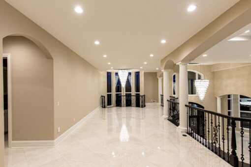 Kingfogl custom home upper hallway with marble floor, iron railing and chandeliers
