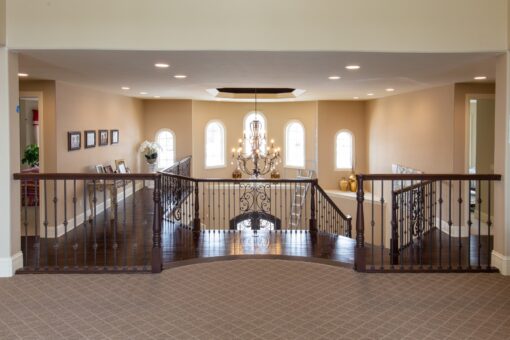 Kingfogl custom home loft with iron railing overlooking the foyer chandelier