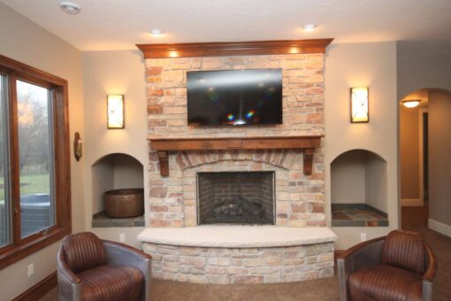 Kingfogl custom home lower-level family room with stone fireplace and media wall