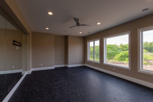Kingfogl custom home lower-level exercise room with rubber flooring and windows