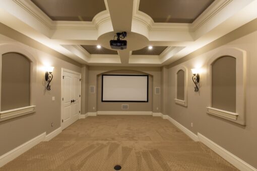 Kingfogl custom home lower-level home theater with tray ceiling and wall sconces