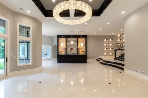 Kingfogl custom home lower level with ring chandelier, lit display wall and marble floor