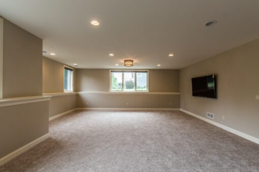 Kingfogl custom home lower-level family room with carpet and wall-mounted TV