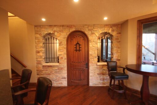 Kingfogl custom home lower level with arched wood door, stone wall and wine room entry
