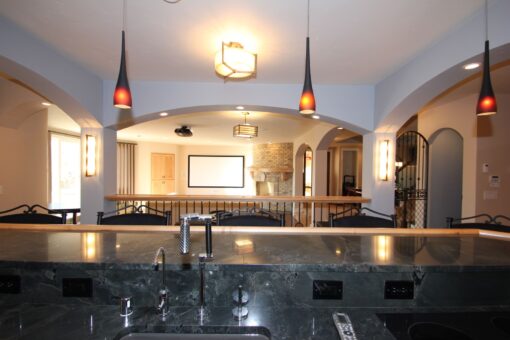 Kingfogl custom home lower-level bar with granite counter and view to the theater