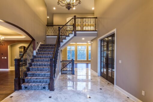 Kingfogl custom home staircase with patterned runner, iron balusters and marble floor