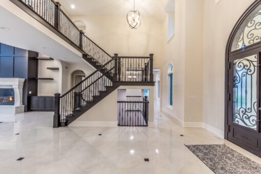 Kingfogl custom home switchback staircase with iron railing and arched iron entry door