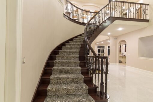 Kingfogl custom home curved staircase with patterned runner and iron railing