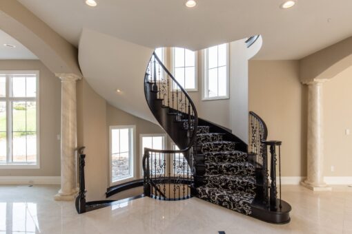 Kingfogl custom home spiral staircase with patterned runner and iron railing