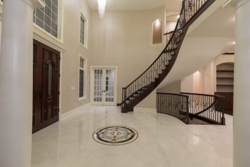 Kingfogl custom home curved staircase above a marble medallion floor