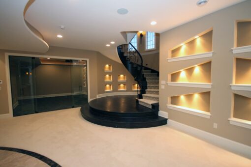 Kingfogl custom home lower-level spiral staircase with lit niches and glass wine room