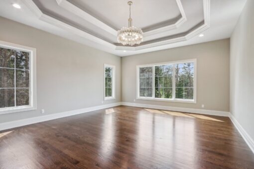 Rangeline primary bedroom with tray ceiling and chandelier