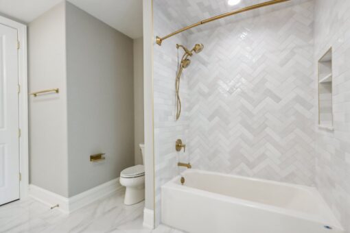 Rangeline tub with herringbone tile and brass fixtures
