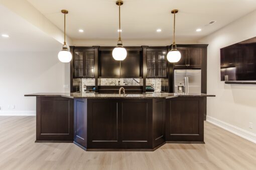 Settlers Circle lower-level bar with dark cabinetry and pendant lights