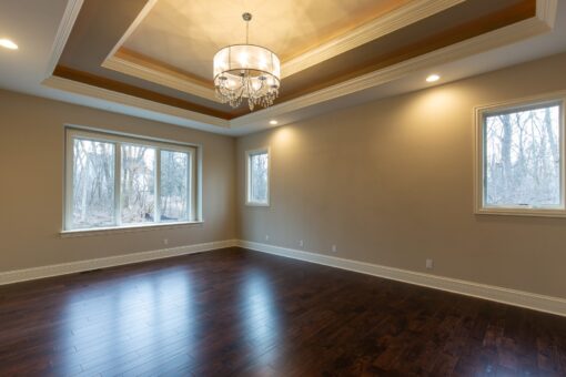 Woodview primary bedroom with tray ceiling and chandelier
