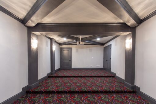 Woodview home theater with beamed ceiling and stepped riser