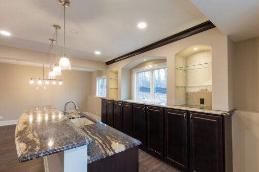 Woodview lower-level bar with granite island and pendants