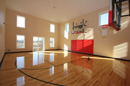 Kingfogl custom home indoor basketball court with red wall pads and tall windows