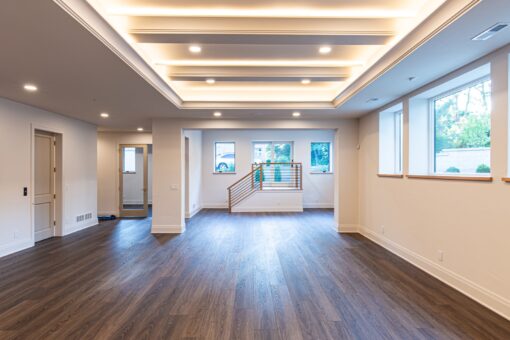 Carlisle lower-level room with lit tray ceiling and staircase