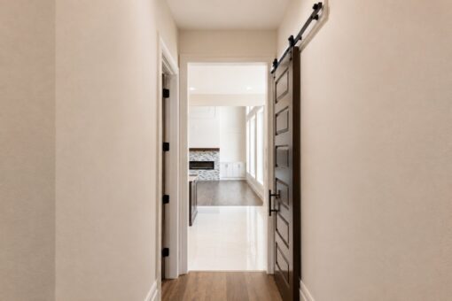 Turnberry custom home in New Berlin by Kingfogl – hallway barn door toward great room