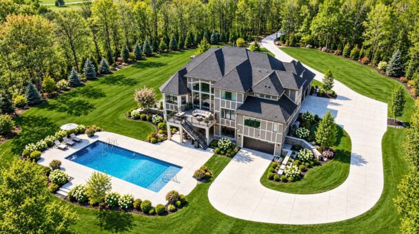 Woodland custom home in West Bend by Kingfogl – aerial rear view with pool and circular drive