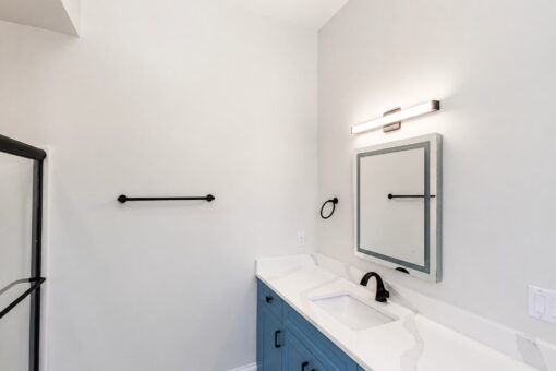 Apex bathroom with blue vanity and lit mirror