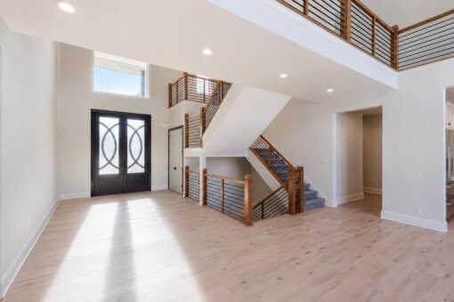Apex foyer with modern iron entry doors and open staircase