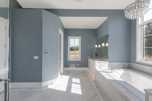 Ridge primary bath soaking tub with blue walls and crystal chandelier